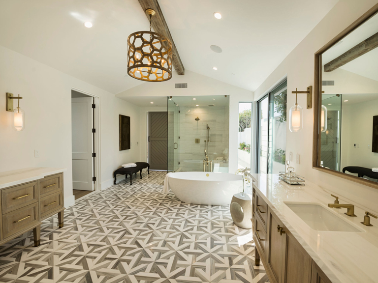 Baño de lujo con bañera exenta, piso de diseño geométrico, mobiliario en madera natural y entrada de luz natural – FRANCO HomeServices