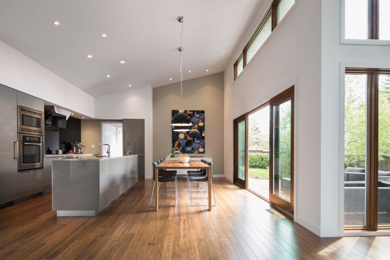 Cocina integral y comedor moderno con isla en mármol y ventanales de piso a techo – FRANCO HomeServices