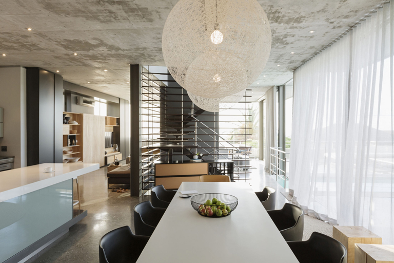 Comedor de estilo industrial con lámparas esféricas, ventanales amplios y cortinas translúcidas – FRANCO HomeServices