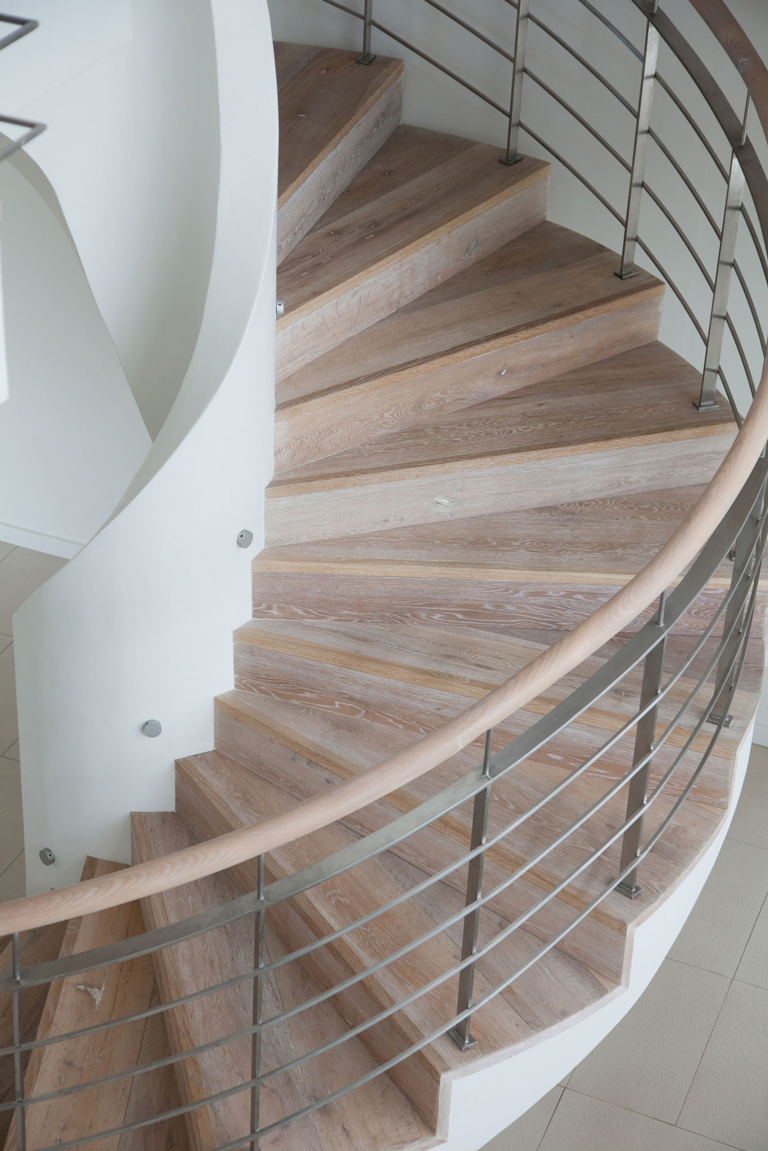 Escalera helicoidal de madera clara con diseño curvo y baranda metálica de estilo contemporáneo – FRANCO HomeServices