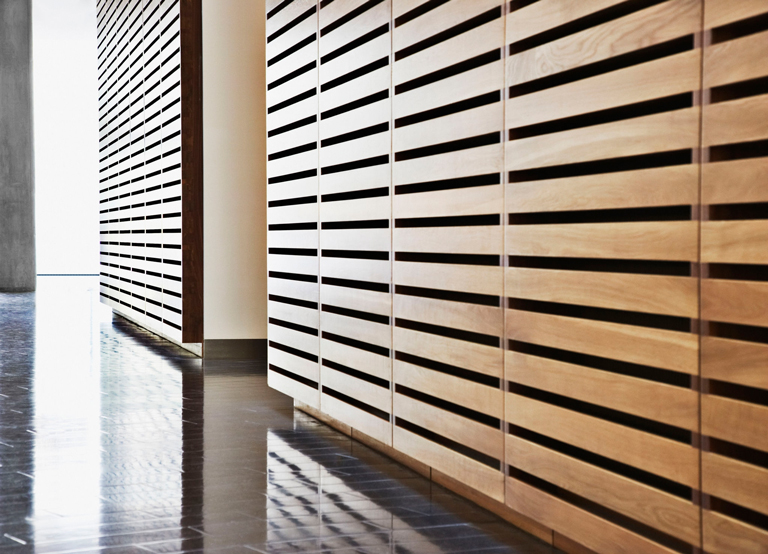 Revestimiento interior con paneles de madera moderna dispuestos horizontalmente en pasillo arquitectónico – FRANCO HomeServices