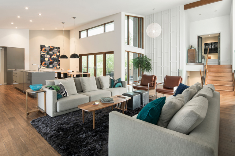 Sala integral de lujo con diseño abierto, pisos de madera y ventanales de luz natural – FRANCO HomeServices